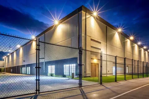 Commercial chain link security fencing surrounding a warehouse facility at night