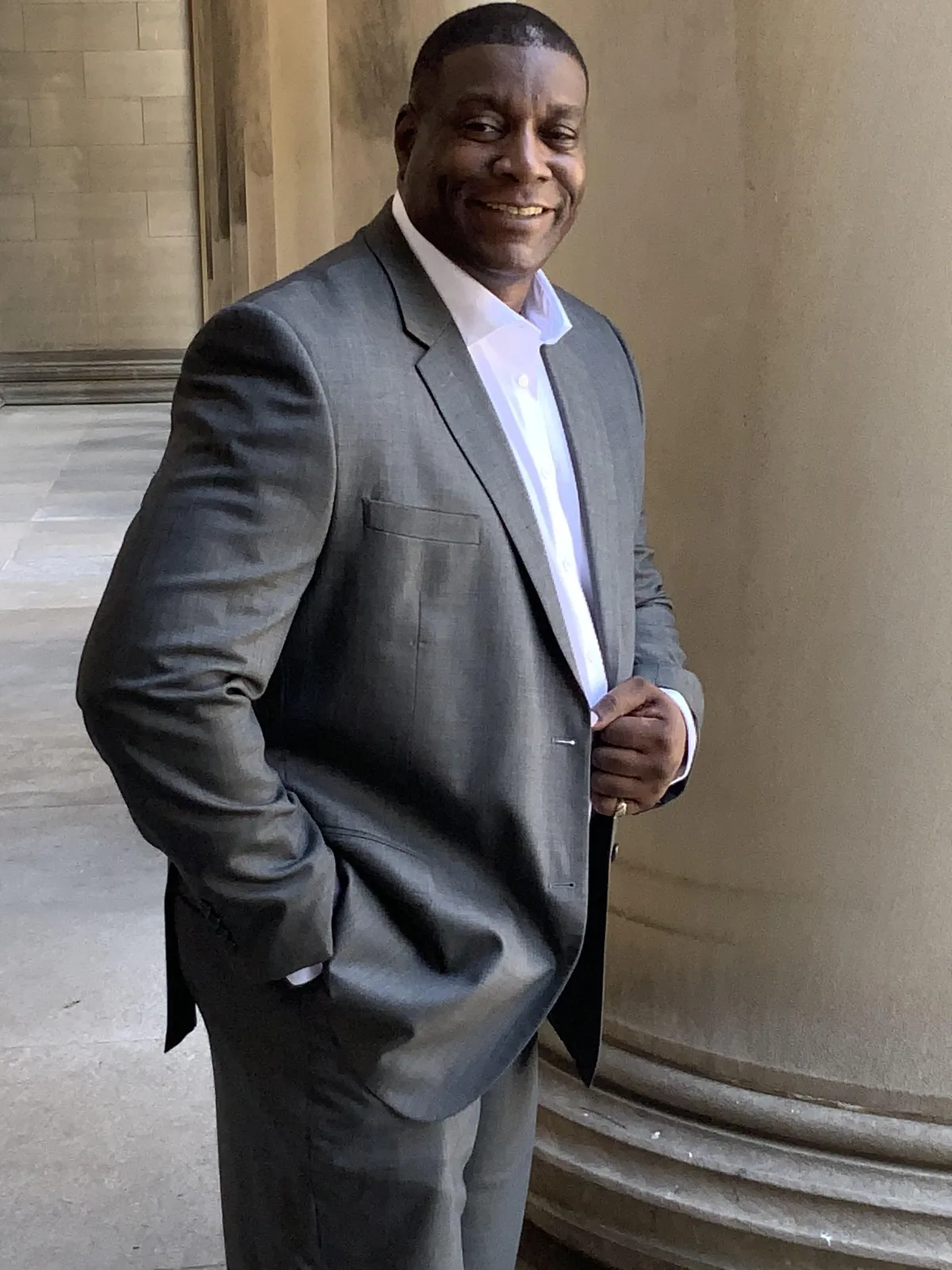 Terence Young, founder of Commercial Broker Academy, confidently smiling in a gray suit while standing beside a columned building—representing trust, leadership, and commercial real estate expertise.