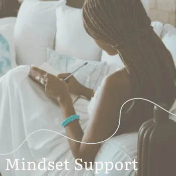 lady sat with back to us on the sofa, white dress, writing in a journal, mindset support for business women mastermind, women with chronic illness