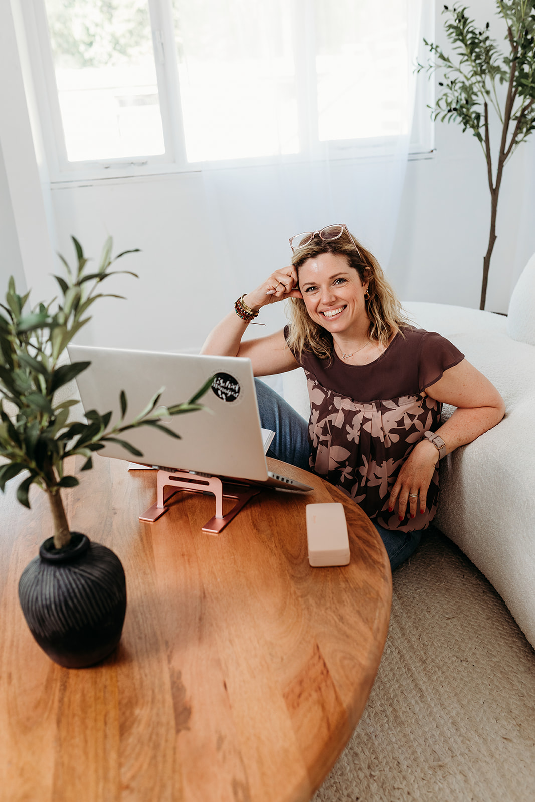 Laura Fox holistic business coach sitting on a wite sofa. Building fully booked businesses with part-time energy
