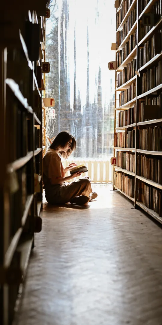 Adult reading on library floor