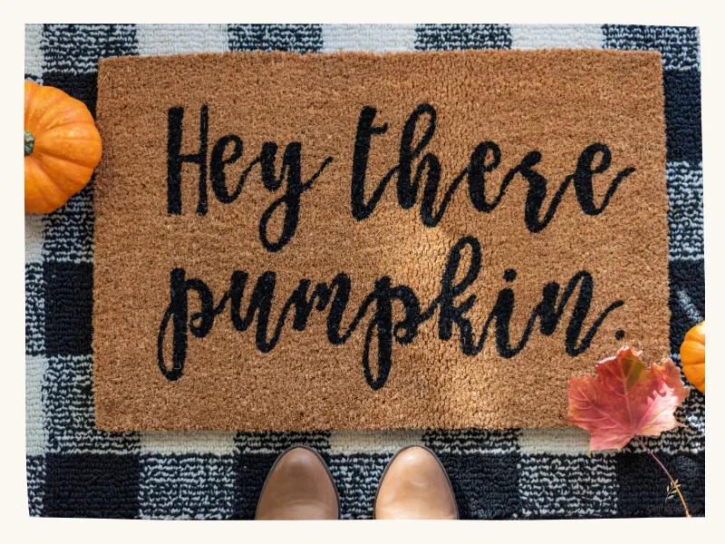 Layered black and white checkered rug and doormat on a fall front porch.