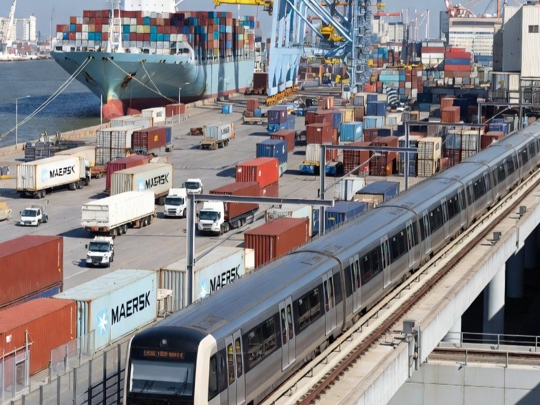 A ship carrying cargo from different companies and a light rail transit