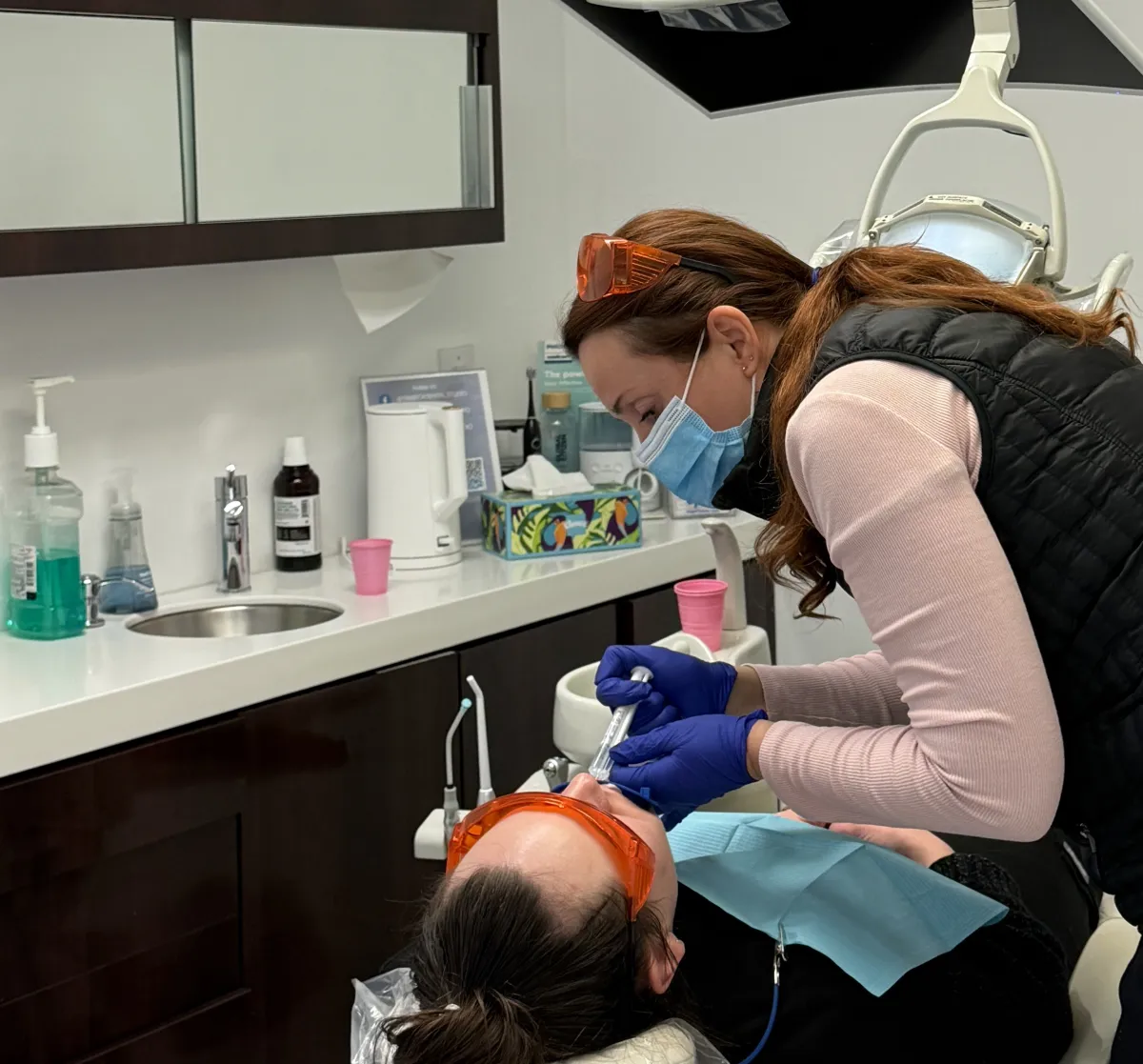a woman sitting in a dentist chair holding up a mirror