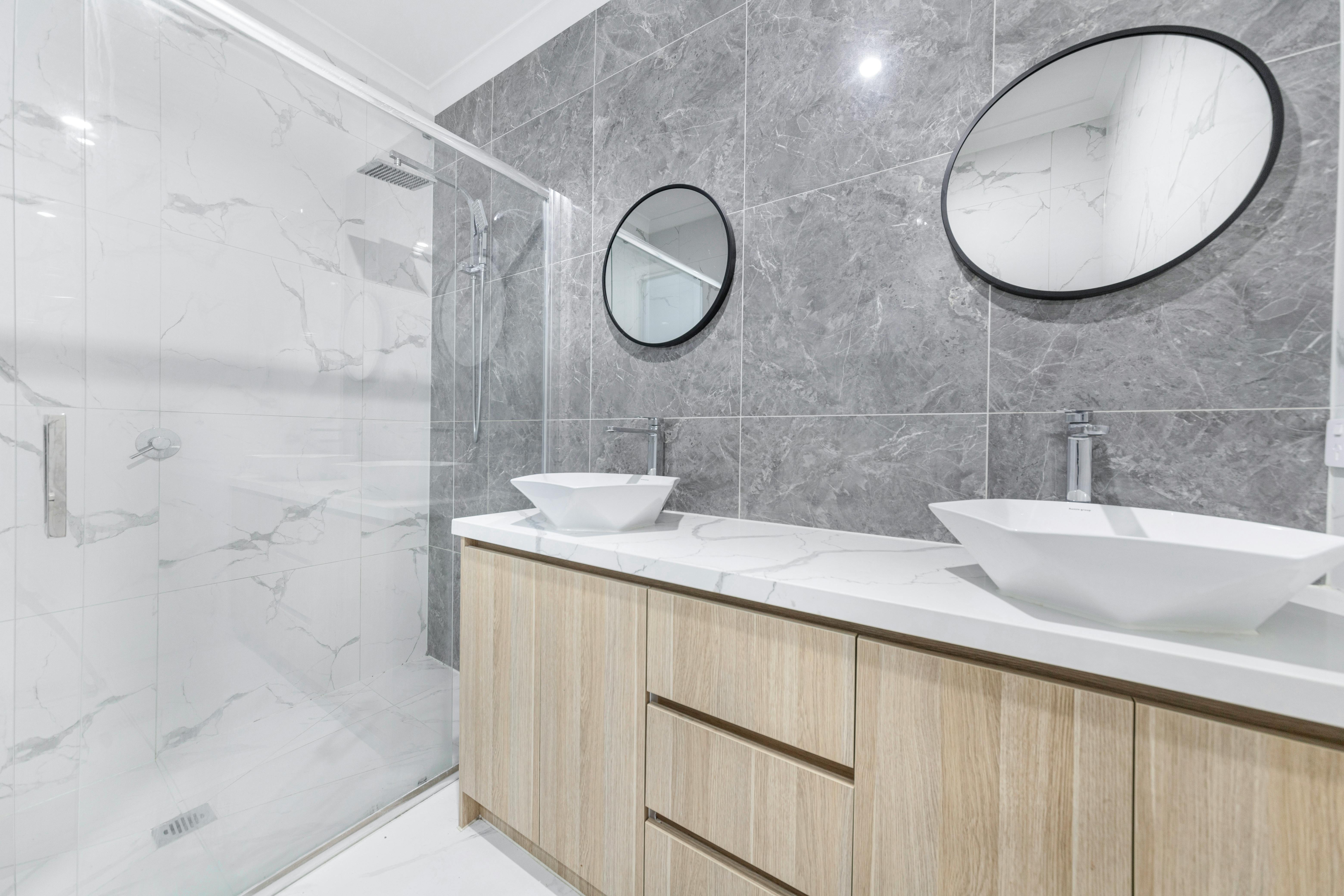 white floor with grey wall tiled bathroom with 2 sinks and shower