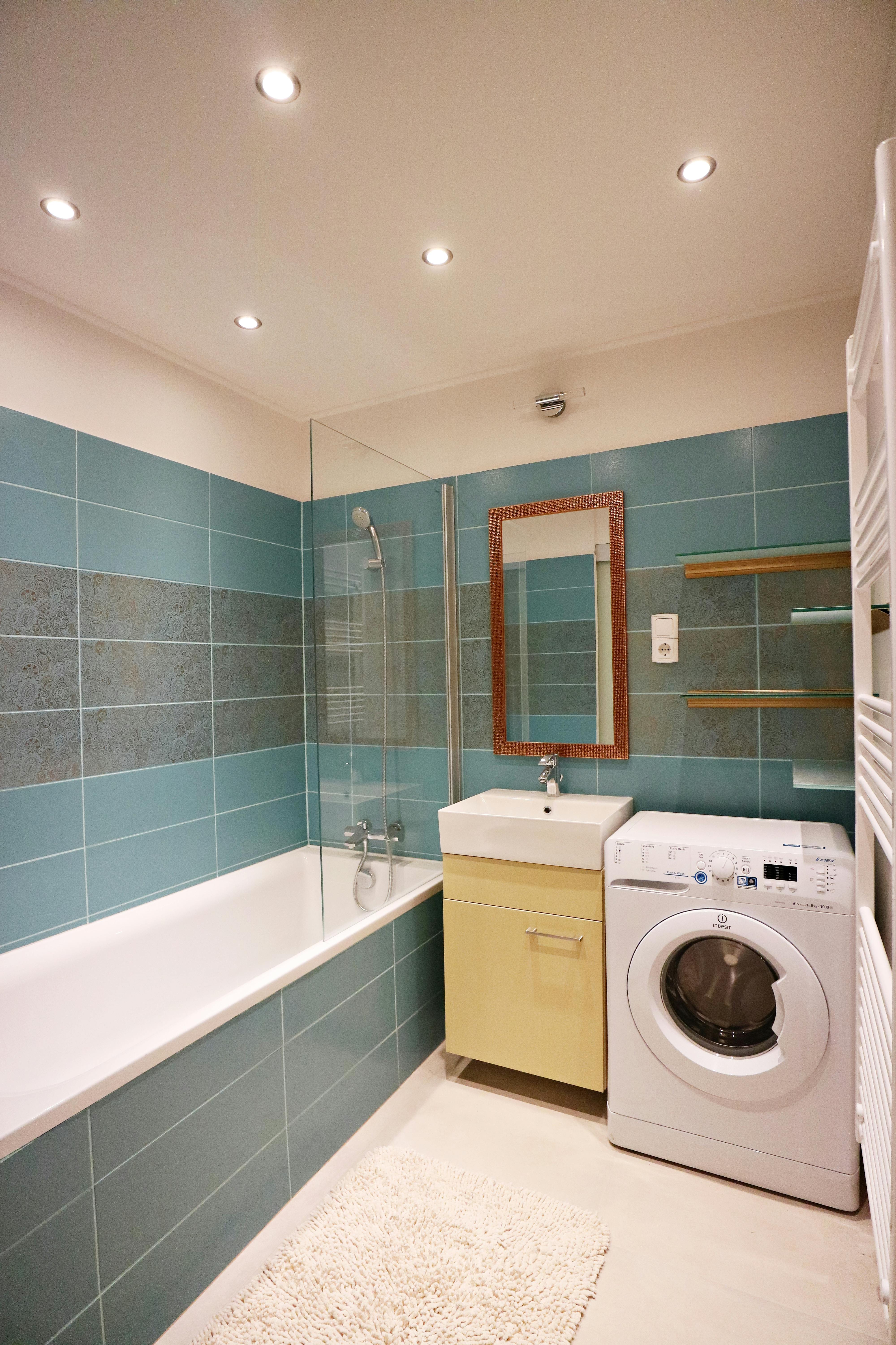 green turqoil tiled with washing machine, sink and bathtub