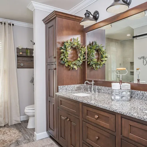 Stylish bathroom vanity featuring a sleek quartz countertop, custom cabinetry with ample storage, and modern brushed gold fixtures. A large, backlit mirror enhances the space, creating a perfect blend of elegance and functionality in this beautifully remodeled bathroom.