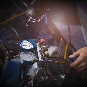 Workshop performing air conditioning service on a vehicle, with a skid-steer loader in the background. Heating and cooling diagnostics in progress.