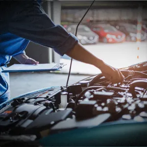 Mechanic inspecting car engine for transmission and drivetrain service