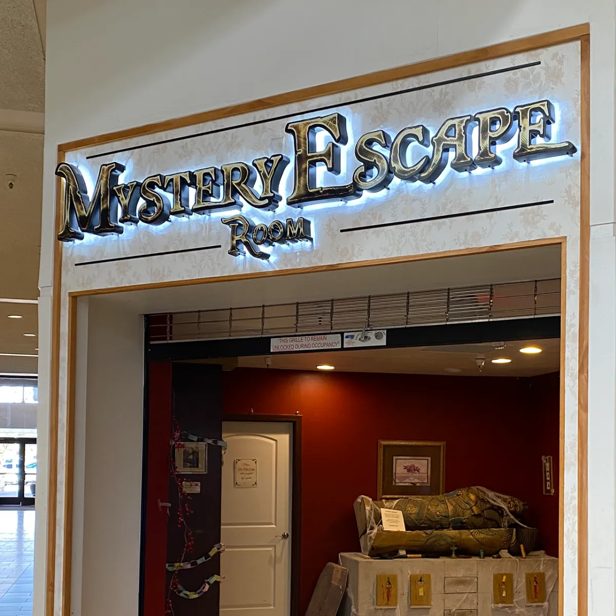 Bright, colorful photograph of a Tucson Mall escape-room set: midcentury props, playful puzzle stations, natural fill lighting and families interacting with immersive props for a lively mood.