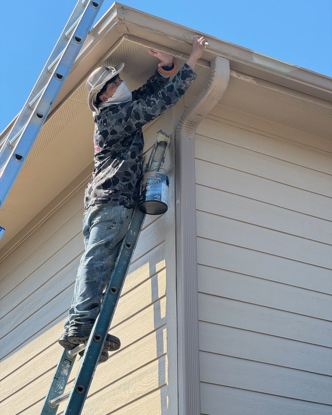 Painter applying finish to exterior trim and fascia on Houston home