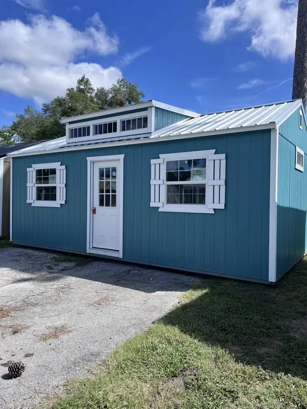 Blue side utility shed with white trim and upper windows at Crossroads Sheds