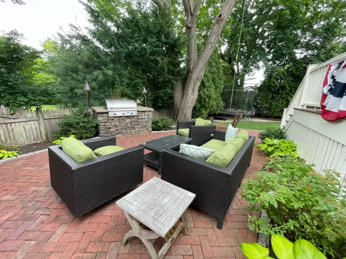 Custom brick masonry patio with outdoor seating area and built-in stone grill station in Marblehead MA backyard landscape design.