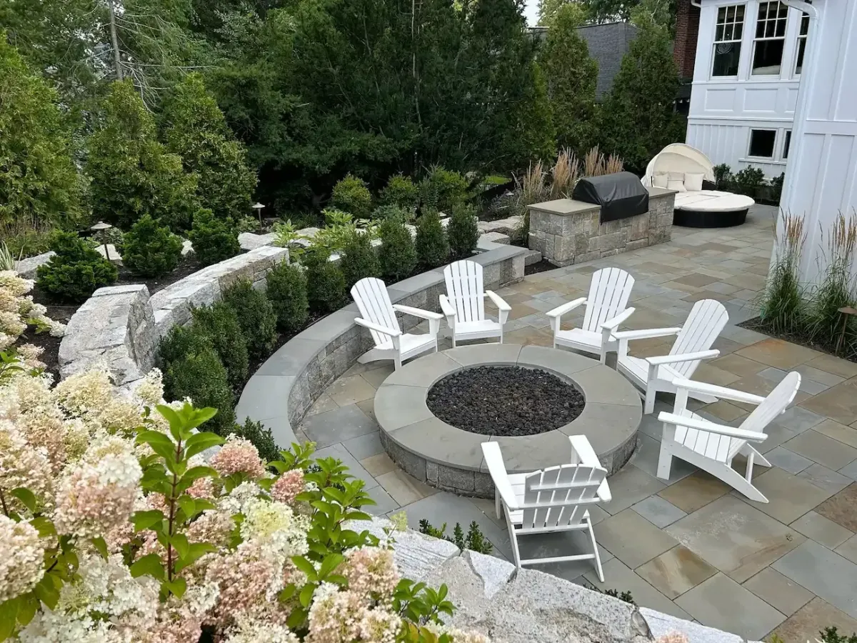 Custom outdoor fireplace and stone fire pit patio installation in Marblehead MA backyard living space.