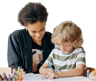 Teacher helping a young boy with schoolwork at a desk.
