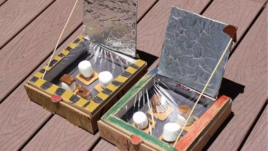 Two homemade solar ovens made from cardboard boxes with reflective foil.
