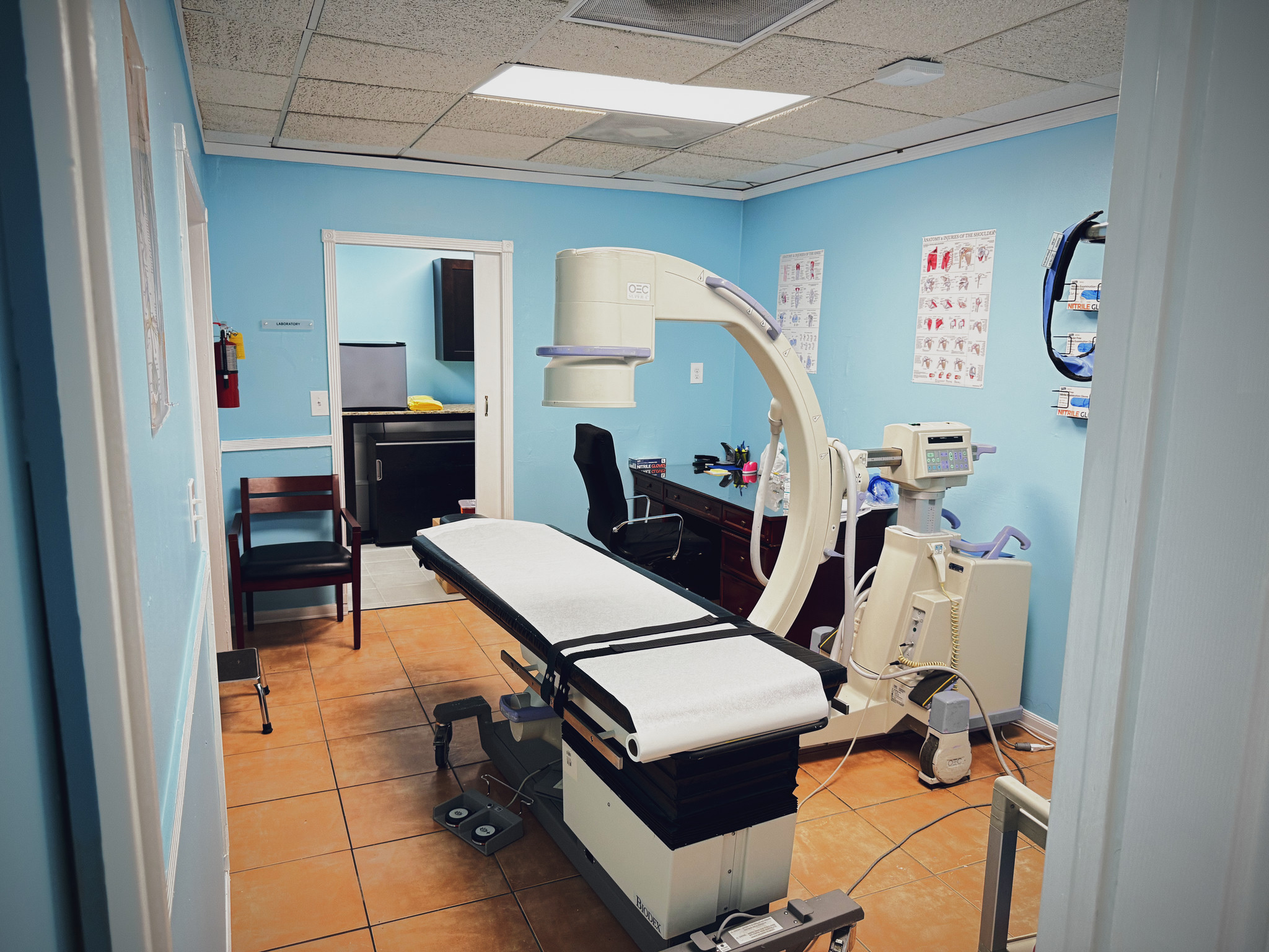 Sala de procedimientos con camilla y equipo de imagen médica con arco en C