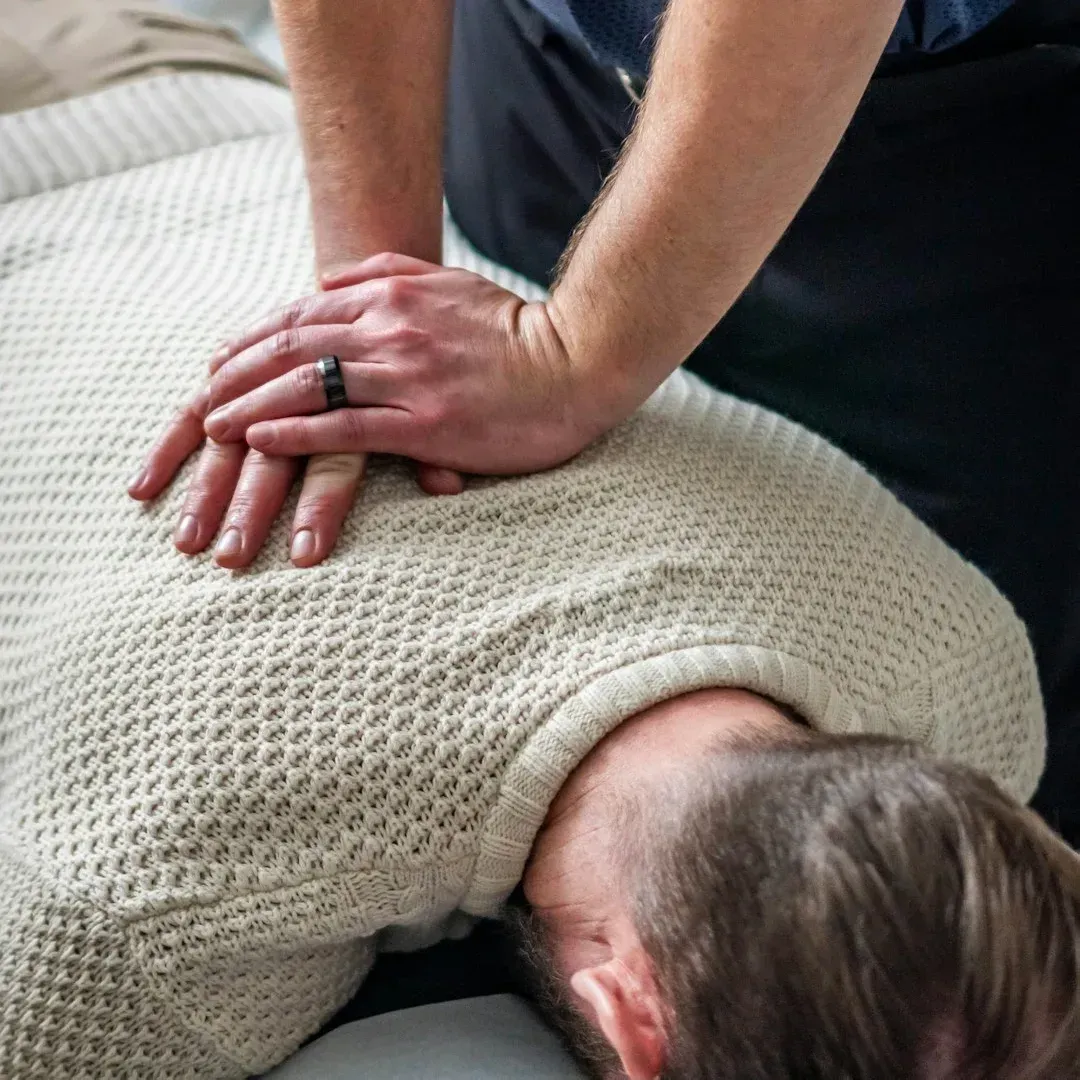 Profesional aplicando terapia manual en la espalda de un paciente acostado boca abajo