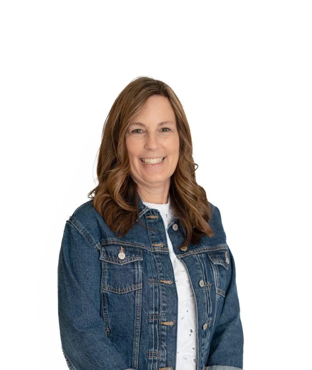 Dr. Maya Chen, an Asian-American woman in her 40s, stands confidently in front of a bookshelf filled with educational books. She wears a navy blazer and glasses, smiling warmly. The background is a well-lit academic office, suggesting expertise and approachability.