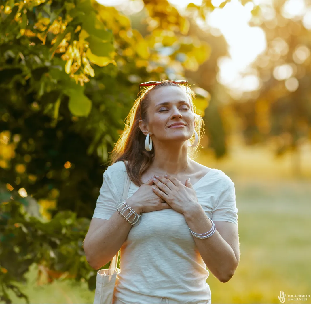 Woman in a park, eyes closed hands on her chest Yoga Health and Wellness