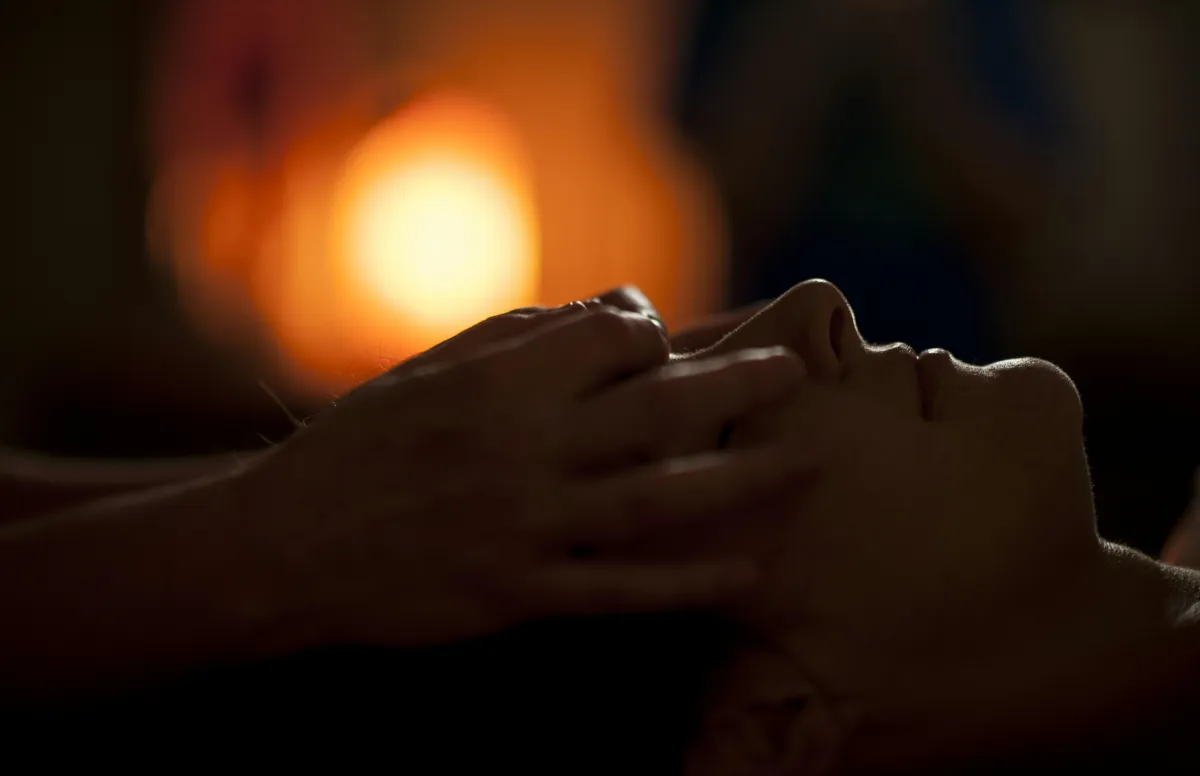 person receiving reiki, practitioner hands on forehead