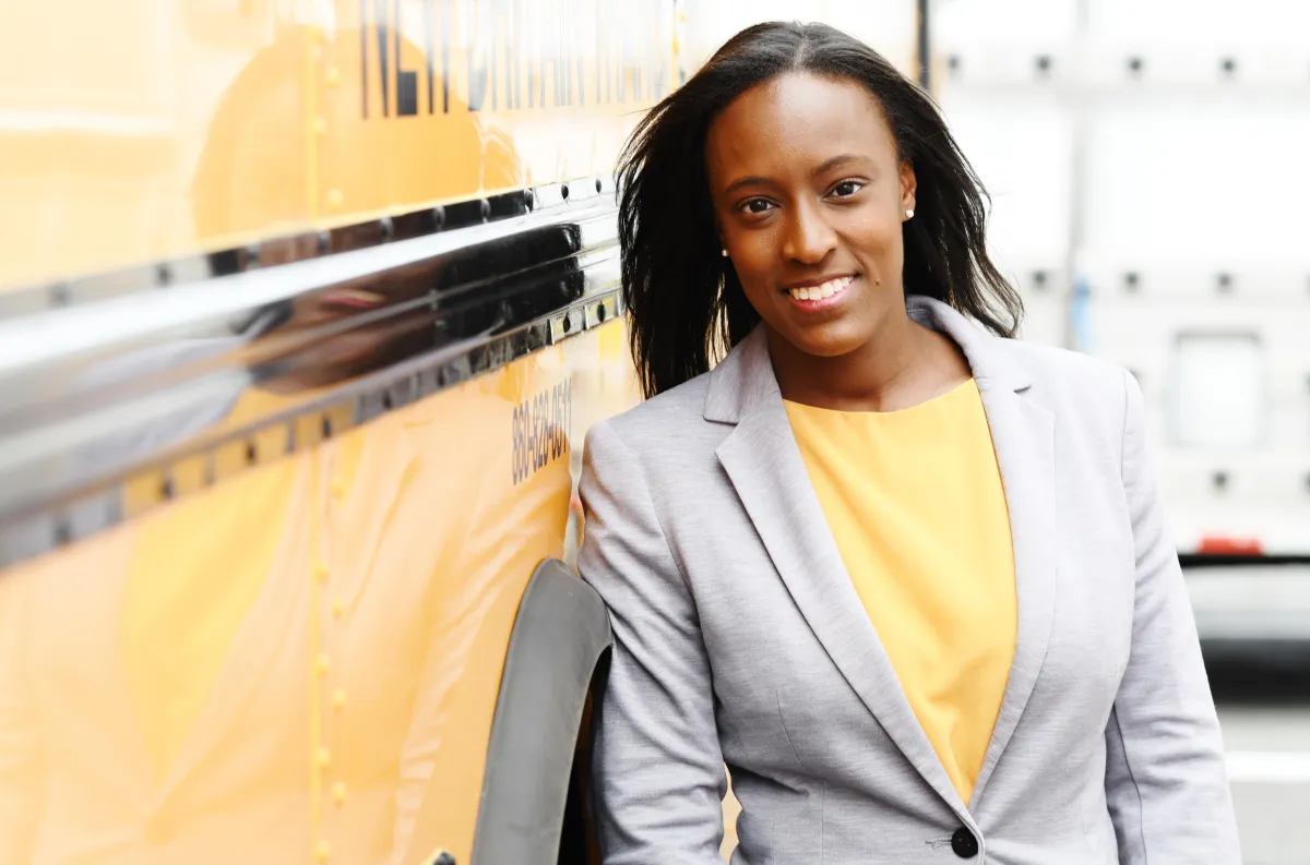 Aigné Goldsby, Esq. standing next to school bus
