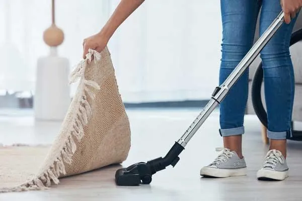 woman sweeping under carpet