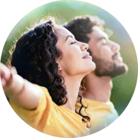 Personas con ojos cerrados y brazos abiertos, conectando con sus emociones mediante la respiración consciente.