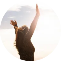 Persona al atardecer con brazos elevados, representando la transformación interior lograda con breathwork.