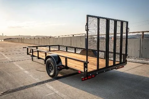 A black utility trailer with a wooden bed and mesh sides, parked on a concrete surface.