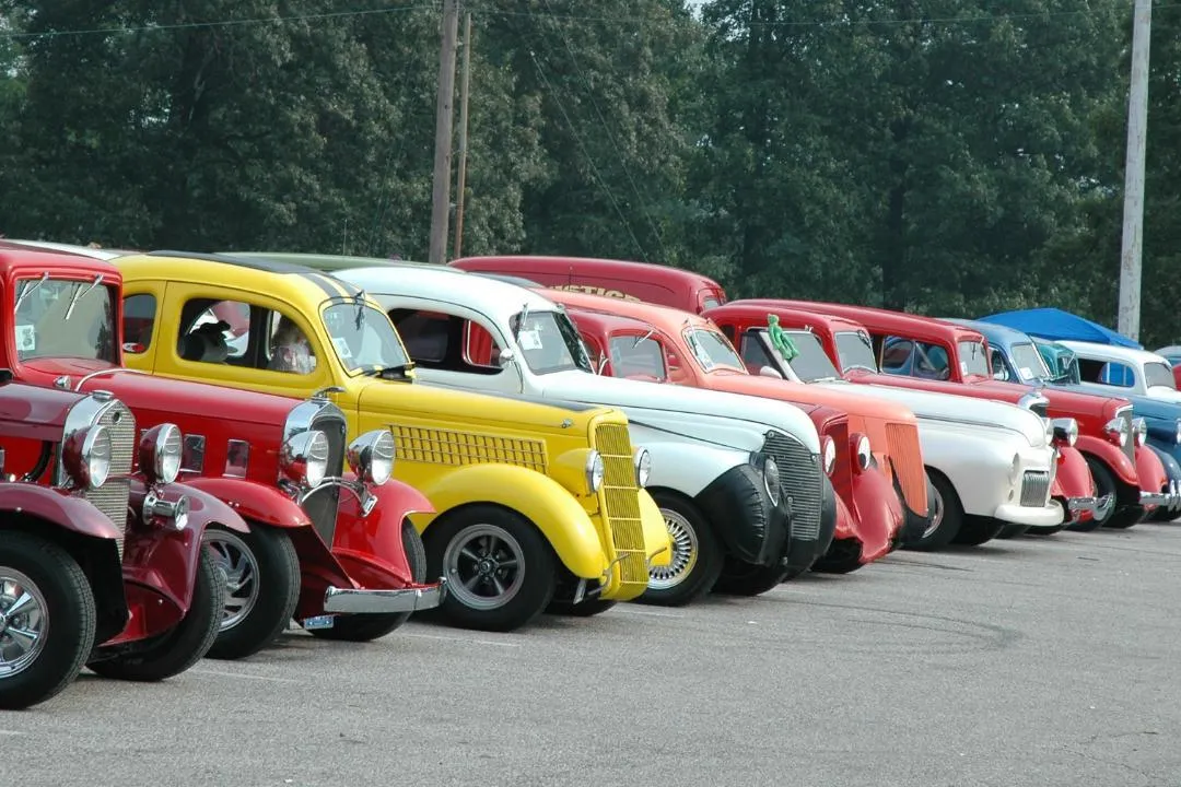 Row of restored antique cars displayed at an outdoor show, highlighting state laws for registering historic vehicles in the USA.