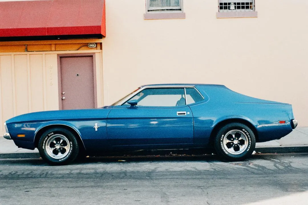 Restored blue vintage Mustang parked on a quiet street, showing the type of vehicle requiring title and tag steps in Florida.