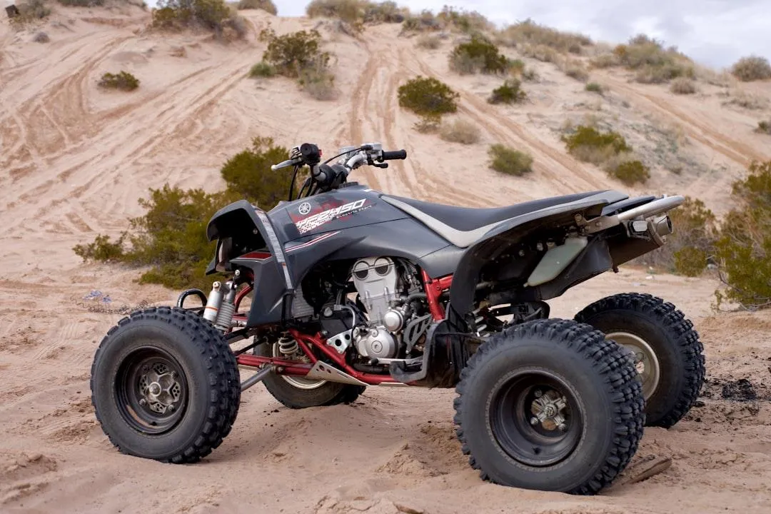 A red all-terrain vehicle (ATV) with large tires and handlebars, designed for off-road use.