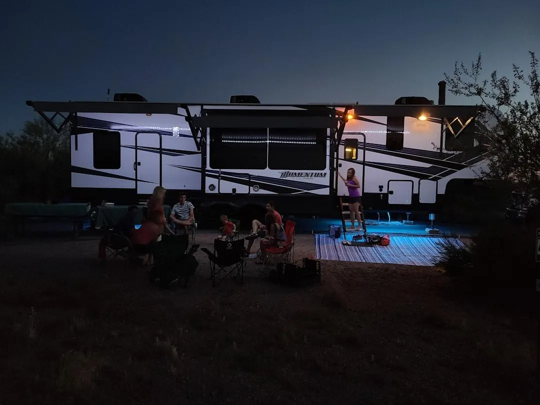 A black utility trailer with a wooden bed and mesh sides, parked on a concrete surface.