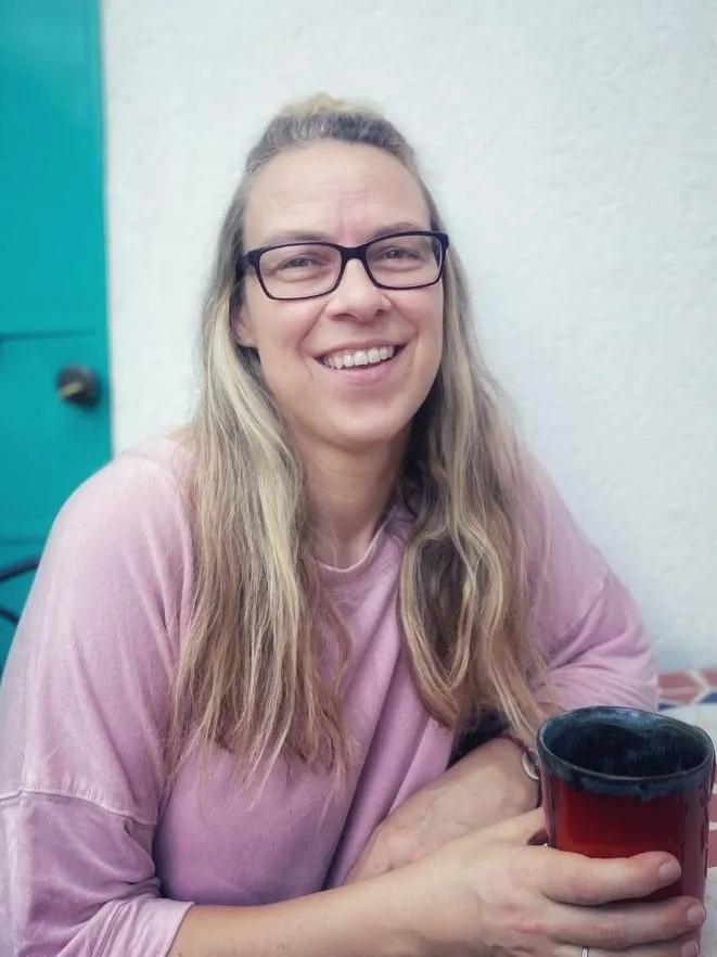 Portrait of Eileen Ranscht smiling and holding a red mug, representing calm and warmth