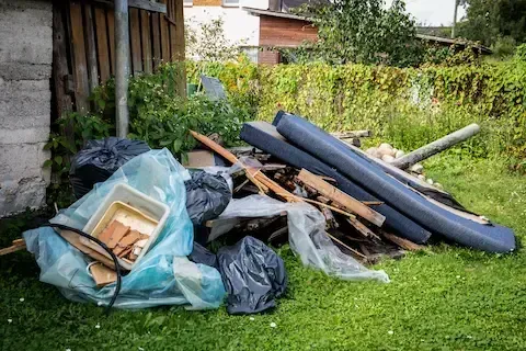 Hoarding cleanout with scattered debris and trash bags in a yard by West Linn Junk Removal.