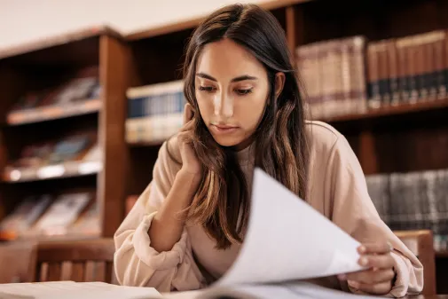 A student studying at a desk in front of a bookshelf