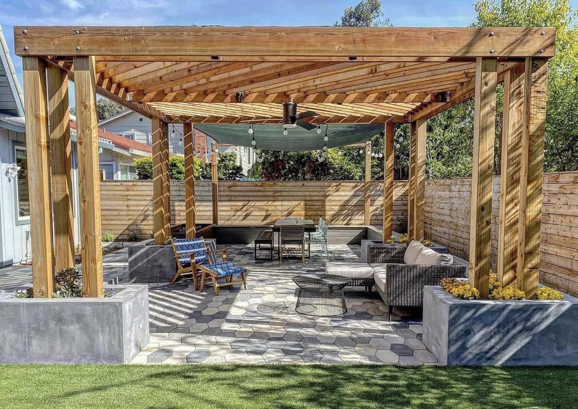 Custom-built wooden pergola with thick rope-wrapped posts, outdoor lounge seating, and paver flooring in a spacious San Diego backyard.