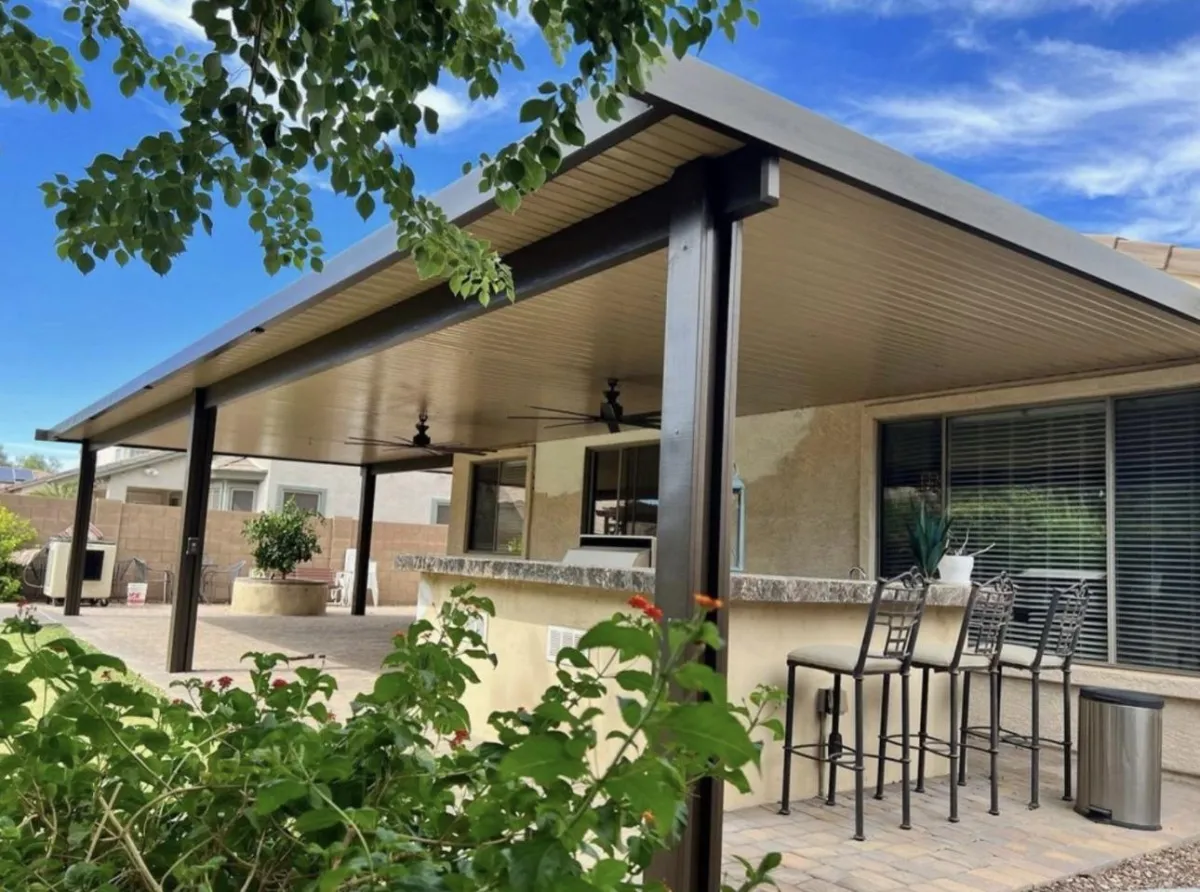 Modern aluminum patio cover attached to the home with built-in ceiling fans and outdoor bar seating.