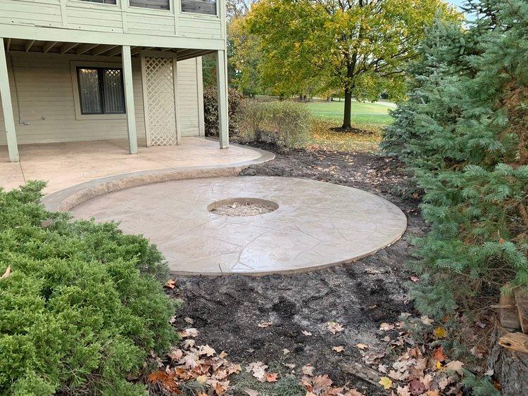 Custom attractive outdoor patio with fireplace located in the middle done by CR Concrete Construction