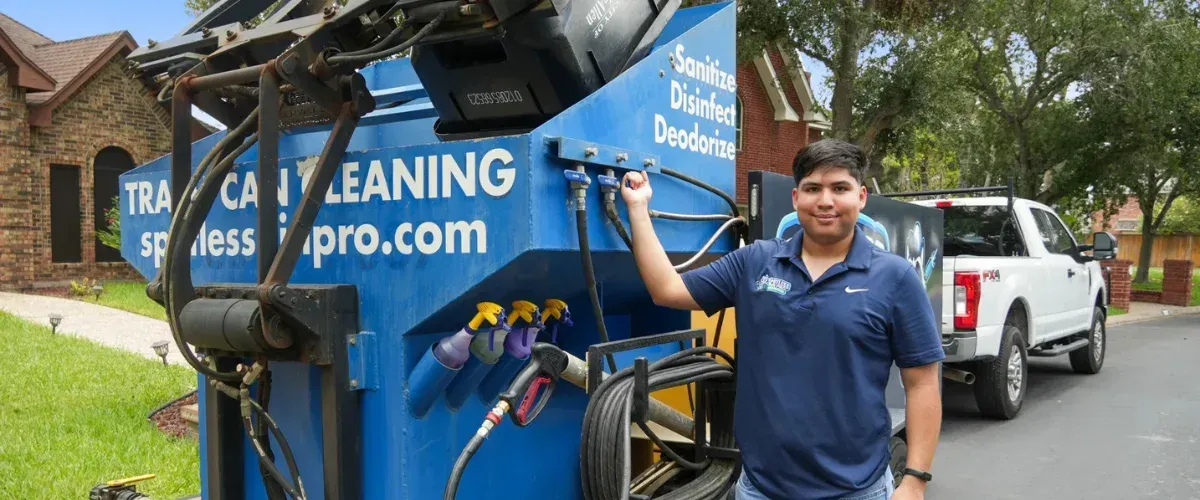 Trash bin cleaning technician standing next to professional cleaning truck in a residential neighborhood