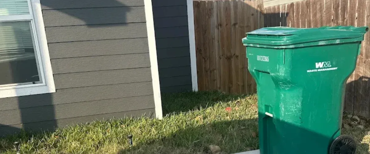 Green residential garbage bin before professional trash bin cleaning service