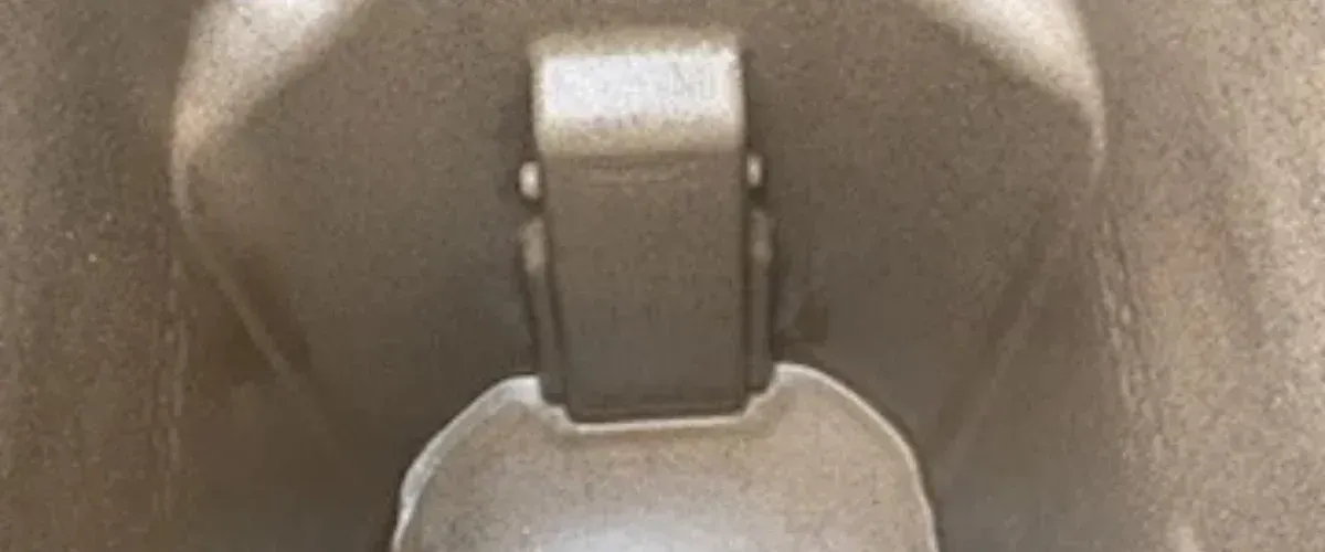 A close-up, abstract, sepia-toned image showing a metal hinge or clasp against a textured background.