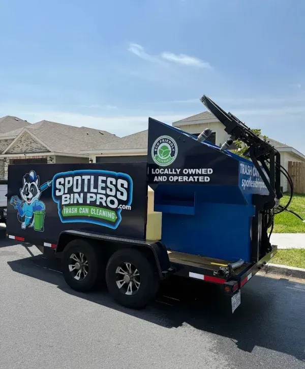 A black trailer with the "Spotless Bin Pro" logo and blue cleaning equipment parked on a residential street.