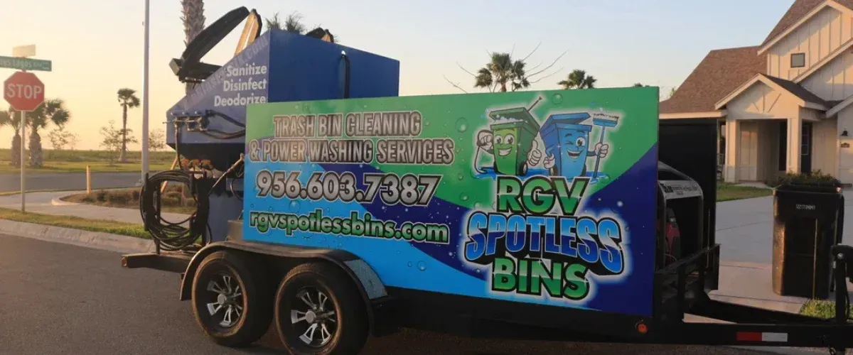 A custom RGV Spotless Bins trailer displaying trash bin cleaning services with a stop sign in the background.