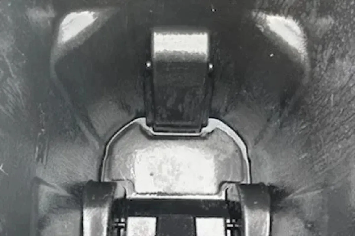 A grainy monochrome close-up of an industrial-looking mechanism with metallic parts and textured surroundings.