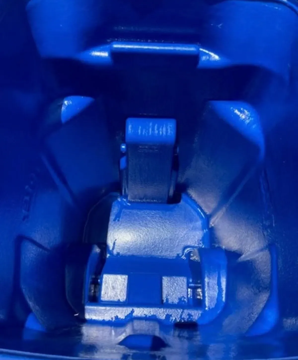 A close-up, top-down view inside a vibrant blue plastic bin, showing textured surfaces and internal structural details.