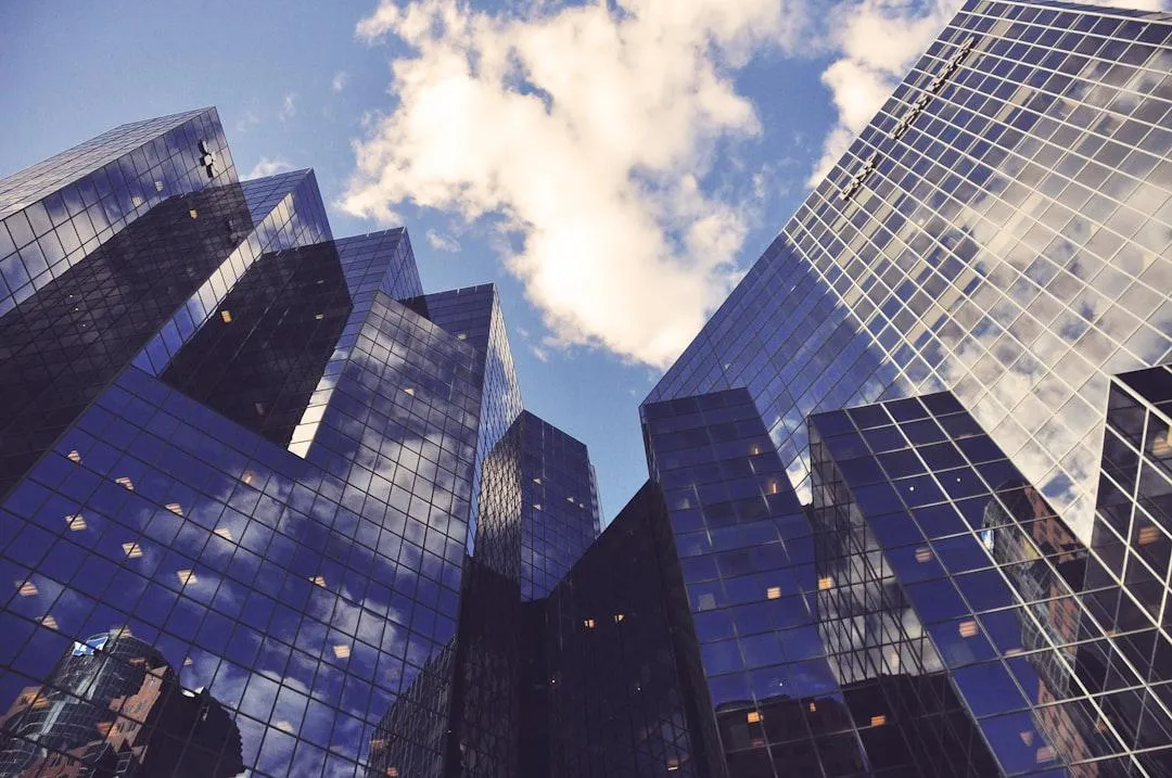 Modern glass office buildings reflecting a blue sky with clouds, symbolizing strategic growth, credibility, and the corporate infrastructure behind Southern Seoulutions Consulting.