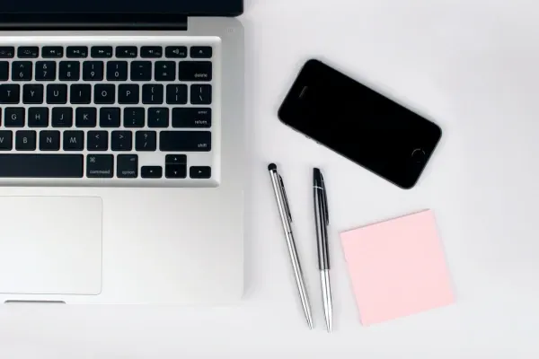 Kuvituskuva jossa läppäri, puhelin, kyniä ja muistipaperia.