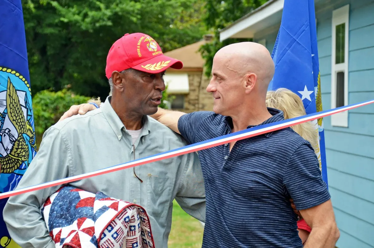 Two veterans, one in uniform, embracing after working together on a Fuller Center home project for another veteran.